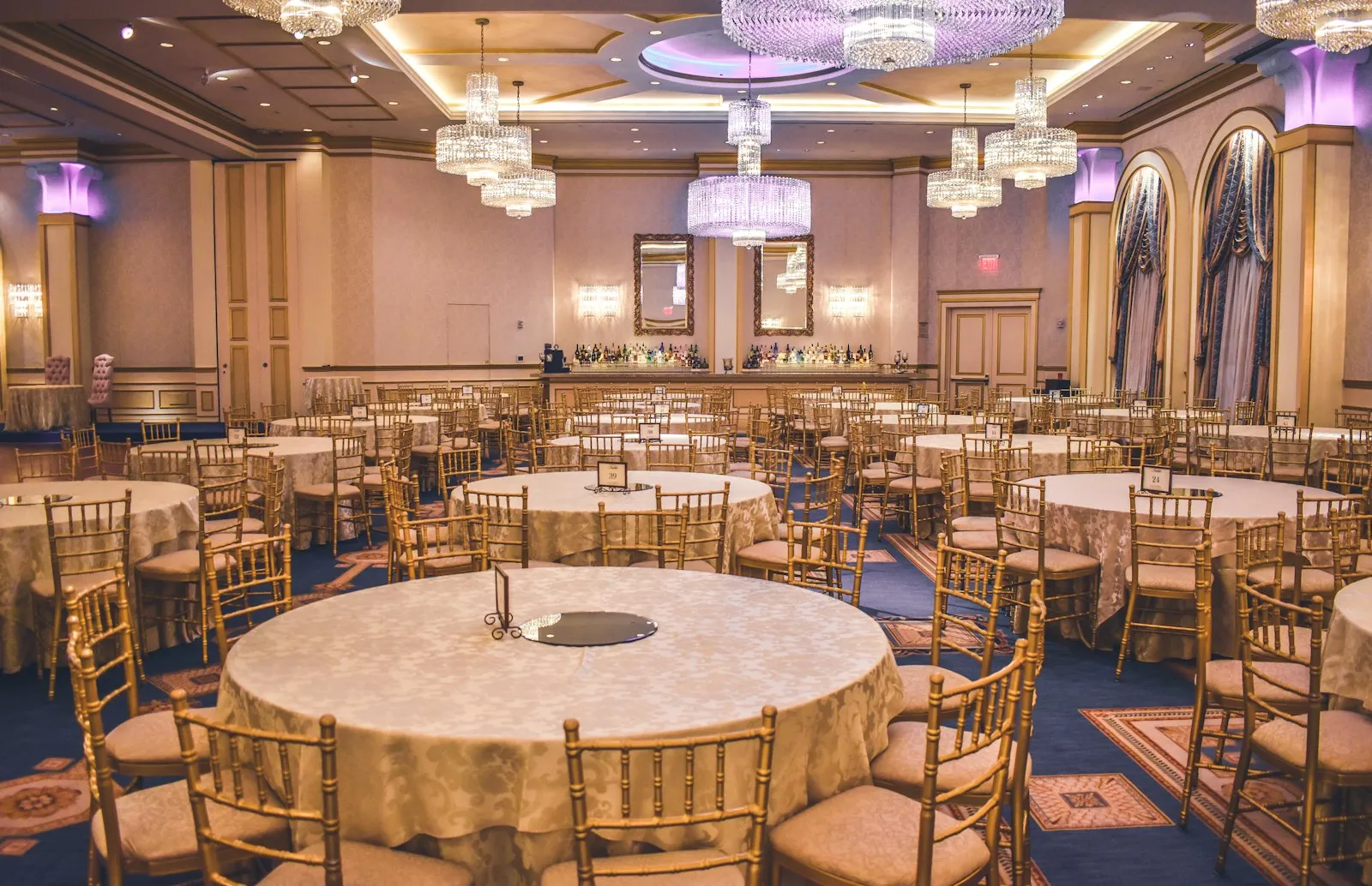 A warmly lit ballroom set for dinner