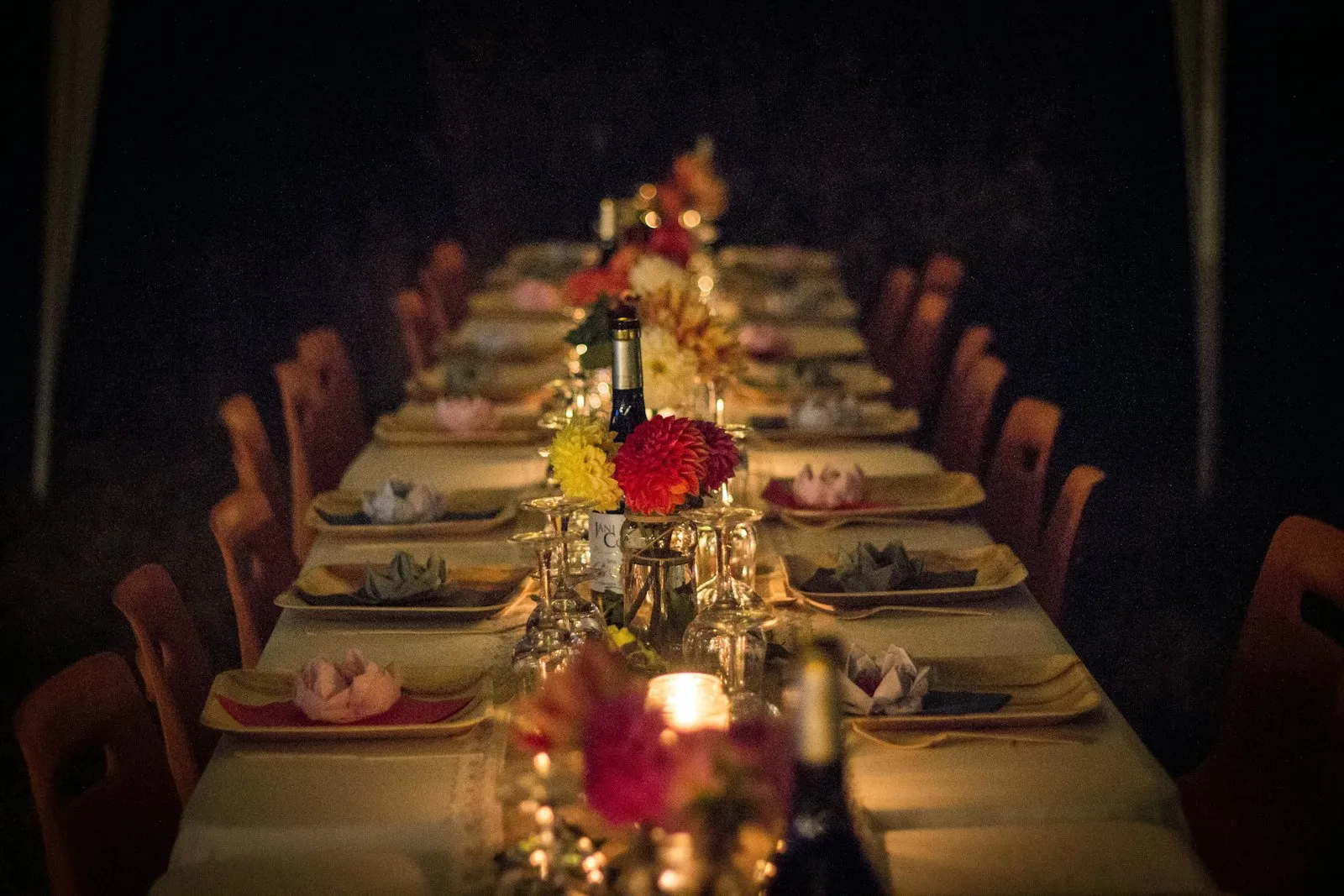 Linen runners, gold chargers, taper candles and bistro lights for one long table.